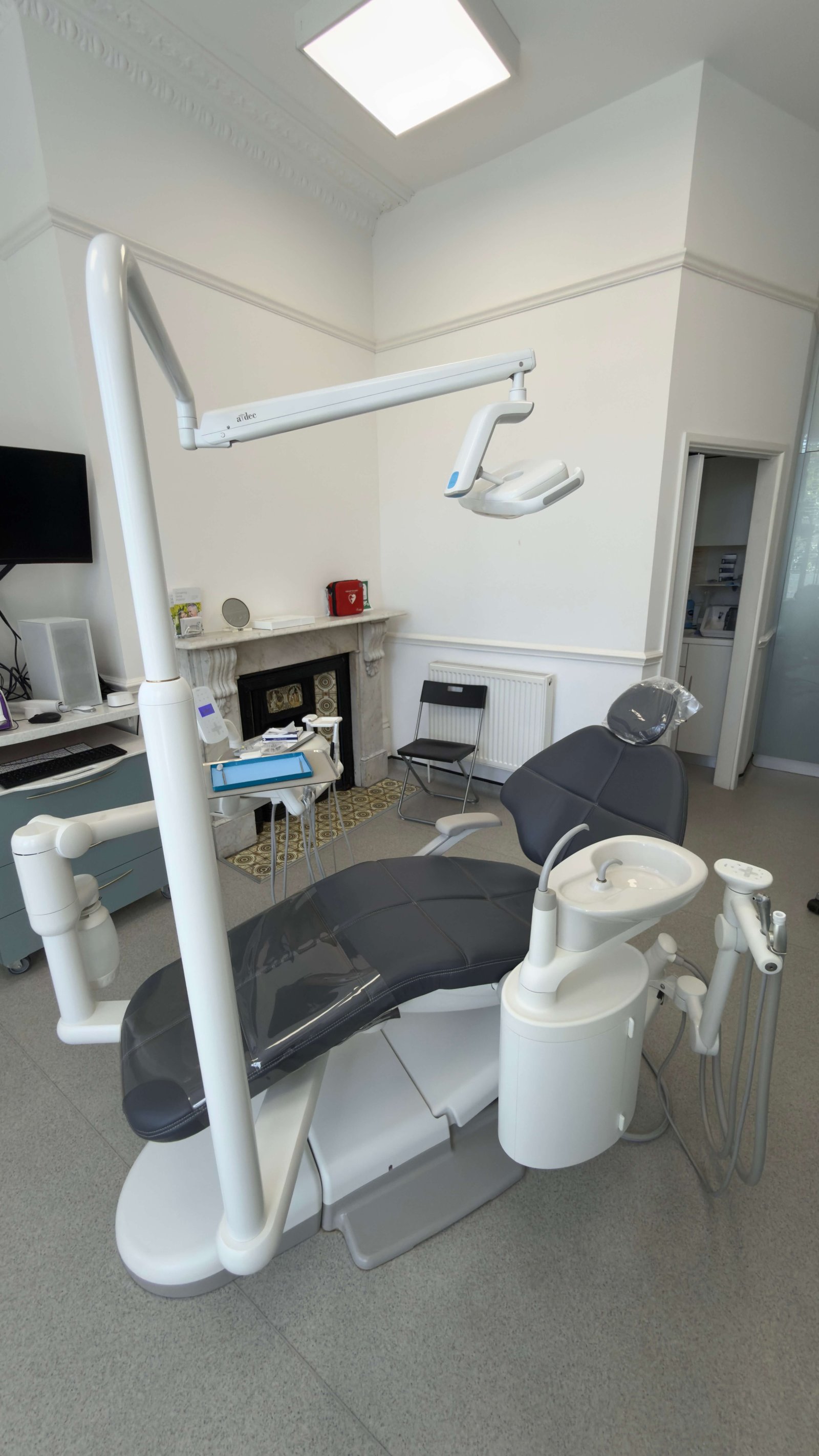 Second treatment room with charcoal dental chair and original marble fireplace